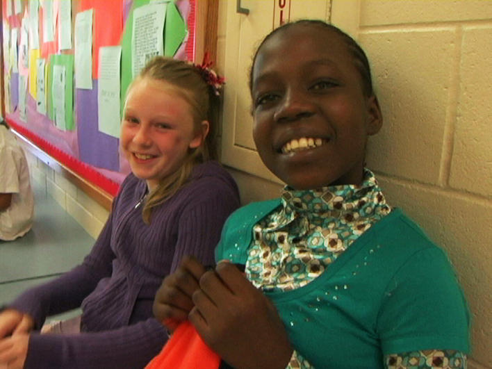 A Darfuri girl with her friend in the school hallway