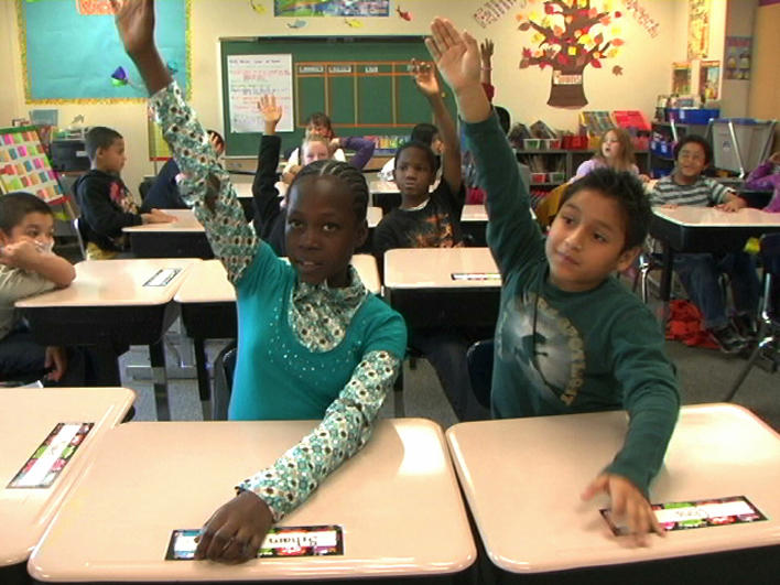 Children raising their hands in elementary school