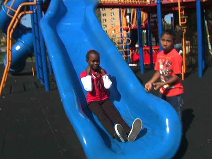 Darfuri girl going down a school playground slide